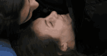 a woman is touching a man 's nose while they are laying down