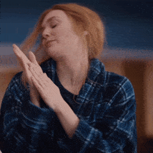 a woman in a blue plaid robe is clapping her hands together