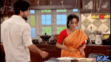 a man and a woman are cooking in a kitchen and the letters kk are on the bottom