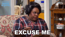 a woman sitting on a couch holding a piece of paper with the words excuse me on it