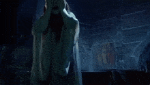 a woman in a white dress with a flower crown on her head is standing in a dark room