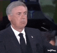 a man in a suit and tie is clapping his hands in a gif