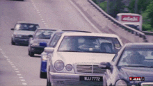 a row of cars are driving down a highway and one has a license plate that says wj7772