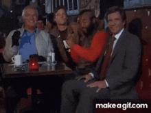 a group of men are sitting at a table with make a gif.com written on the bottom