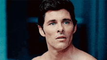 a shirtless man with blue eyes is looking at the camera and making a funny face .