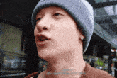 a close up of a man wearing a beanie and earrings