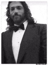 a man with long hair wearing a tuxedo and bow tie