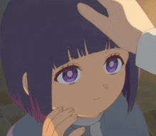 a little girl with purple eyes is being touched by a person 's hand .