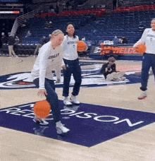a group of people are playing basketball on a court with a welcome sign behind them