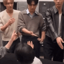 a group of young men are standing next to each other in a room with lockers .