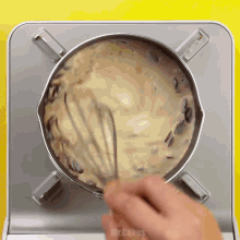 a person is whisking something in a pot that says mr cakes on the bottom