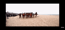 a group of people dancing on a beach with the word vevo at the bottom of the screen