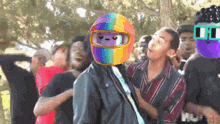 a man wearing a rainbow helmet stands in front of a crowd of people