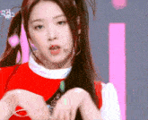a close up of a girl with pigtails on a stage with a pink background