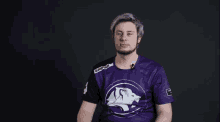 a man is wearing a purple shirt with a white lion on it