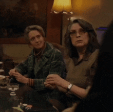 two women sitting at a table with glasses on