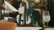 a girl in a green dress is sitting at a table with a plate of food
