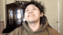 a man wearing a hoodie is making a funny face in front of a door .