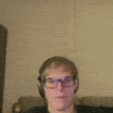 a man wearing glasses and headphones is sitting on a couch .