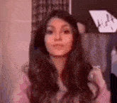 a woman with long brown hair is wearing a pink sweater .