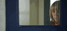 a woman is looking out of a window with a blue frame