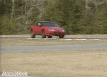 a red car is driving down a dirt road with motorweek written on the bottom