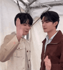 two young men are standing next to each other and giving each other a high five