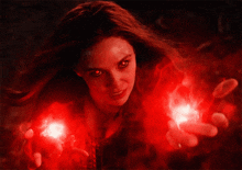 a woman with red eyes is holding a red light in her hand .
