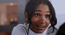 a close up of a woman wearing a white turtleneck sweater and earrings .