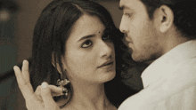 a man and a woman are looking at each other and the woman has a bindi on her forehead