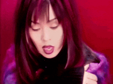 a close up of a woman 's face with her eyes closed and purple hair .