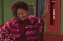 a woman in a pink jacket is standing in front of a fire extinguisher .