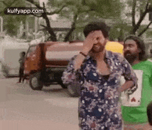a man is covering his face with his hand in front of a truck .