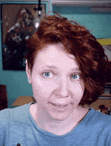 a woman with red hair and blue eyes smiles for the camera