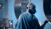 a person wearing a hat and headphones is standing in front of a washing machine