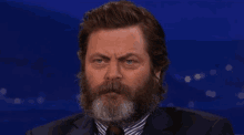 a man with a beard and mustache is wearing a suit and tie and smiling .
