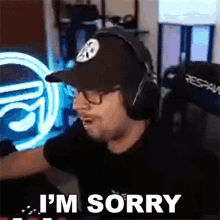 a man wearing headphones and a hat is saying i 'm sorry in front of a computer screen .