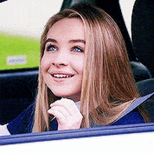 a woman is sitting in the back seat of a car smiling .