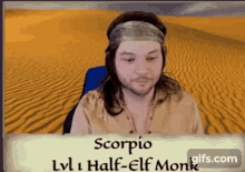a man with long hair and a headband is sitting in front of a sandy desert .