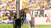 a soccer goalie is trying to stop a soccer ball from hitting the net .