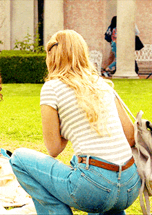 a woman in a striped shirt and blue jeans is squatting down