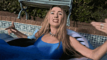 a woman in a blue bathing suit is laying in a swimming pool