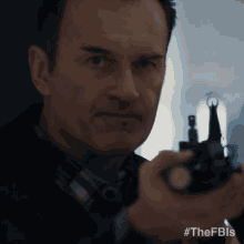 a close up of a man holding a gun with the hashtag #thefbis at the bottom