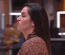a woman with long hair is making a funny face while wearing a leopard print top .