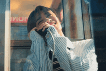 a man wearing a striped shirt and tie talking on a phone