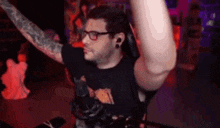 a man wearing glasses and headphones is dancing in a dark room with his arms in the air .