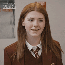a girl in a school uniform is smiling in front of a sign that says son of a critch