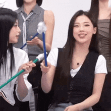a group of young women are sitting next to each other holding sticks and smiling .