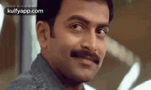 a man with a mustache is making a funny face and looking at the camera .