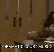 a man in a suit and tie is sitting at a table with the words dramatic court music written on the table